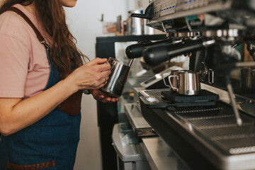 A woman barista prepares a fragrant cappuccino. Making delicious coffee. Barista holds milk for cappuccino