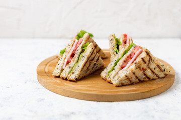 sandwich with ham cheese tomatoes lettuce onions on cutting board. Classic club sandwich with whole grain bread