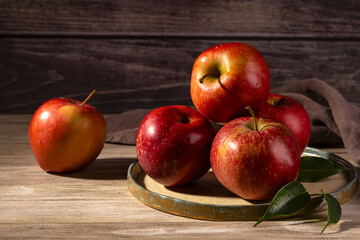 Fresh apples on a plate on a wood background.