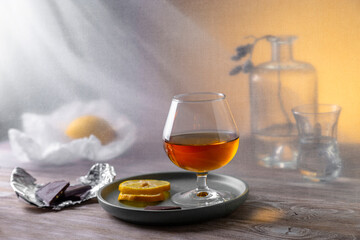 Still life with cognac in a glass and chocolate on a wooden table