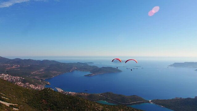 Aerial wide angle shoot of 2 tandem paragliders soaring in horizon - Panoramic Kas Antalya view in the background