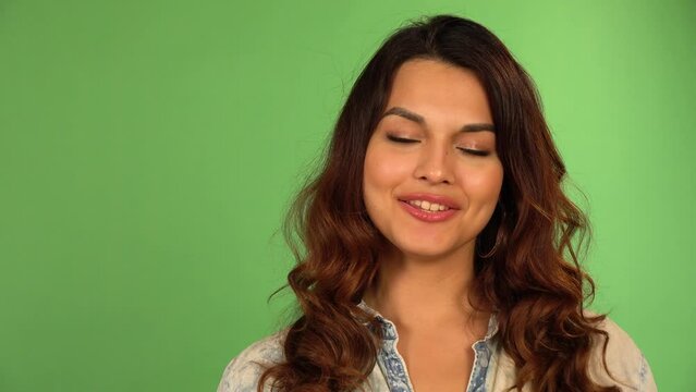 A young beautiful Caucasian woman talks to the camera with a smile - closeup - green screen background