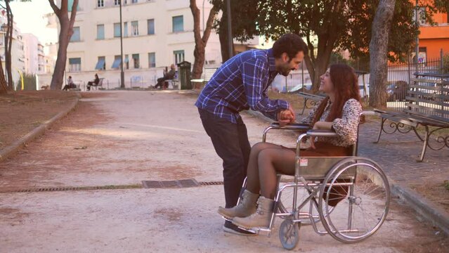 friendship, solidarity - young man join his friend using wheelchair at park