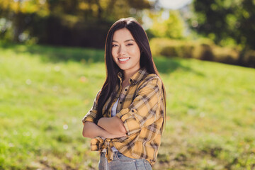 Fototapeta na wymiar Photo of shiny confident young woman dressed plaid shirt walking smiling arms crossed outside nature countryside landscape