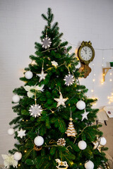 Christmas and New Year photo studio, green tree, soft chair, garlands stars, clock on a white wall (7). Idea for holiday like Christmas and New year, for covers books, magazines, articles.
