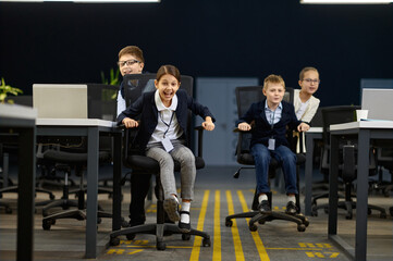 Fototapeta premium Business children having fun riding office chair