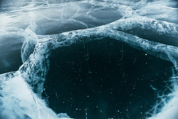 The space magical deep Baikal ice with cracks before your eyes. Close-up view.