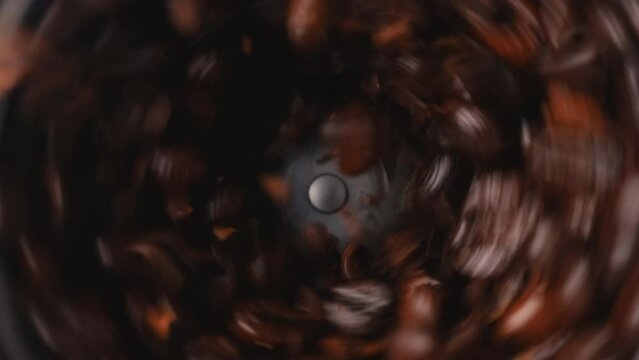 Top view of Roasted coffee beans grinding by Electric coffee grinder, slow motion, Extreme Close-up 
