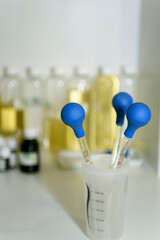 Laboratory instruments close-up. Measuring pipettes and a beaker on a white table in a cosmetic laboratory. Set of pipettes with rubber bulbs.