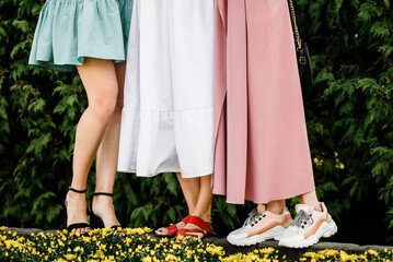 Legs of three young women in trendy summer shoes, closeup photo