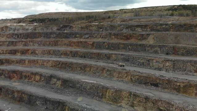 Aerial yellow belaz earthmoving truck in riding in granite open pit quarry.