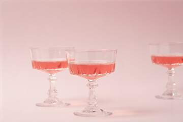 Three crystal glasses of rose sparkling wine or champagne on pastel pink background. Summer drink concept. Minimal creative composition with copy space.