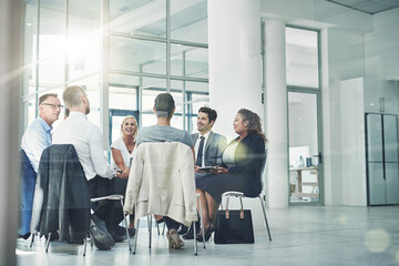 Planning their companys course. Shot of a group of coworkers talking together while sitting in a circle in an office.