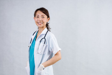 Happy beautiful female doctor in medical coat standing with crossed arms isolated on white.Asia look