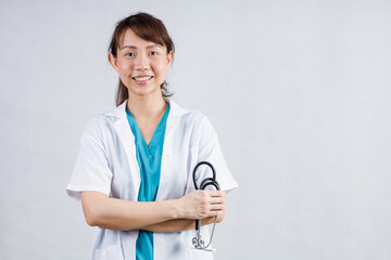 Happy beautiful female doctor in medical coat standing with crossed arms isolated on white.Asia look