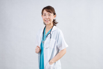 Happy beautiful female doctor in medical coat standing with crossed arms isolated on white.Asia look