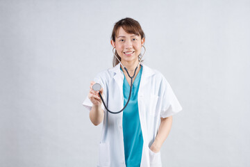 Happy beautiful female doctor in medical coat standing with crossed arms isolated on white.Asia look