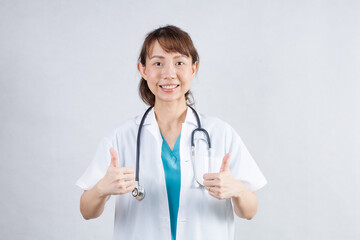 Happy beautiful female doctor in medical coat standing with crossed arms isolated on white.Asia look