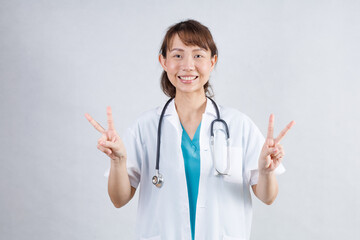 Happy beautiful female doctor in medical coat standing with crossed arms isolated on white.Asia look