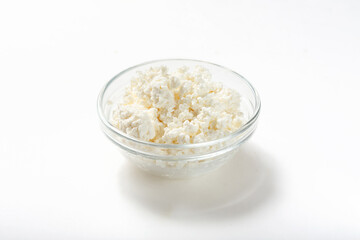 Cottage cheese crumbly on a white background in a glass bowl