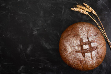 Rye bread and wheat on a dark table, top view