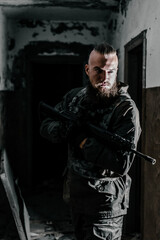 a male military soldier in an abandoned building with a gun poses, shoots and takes aim