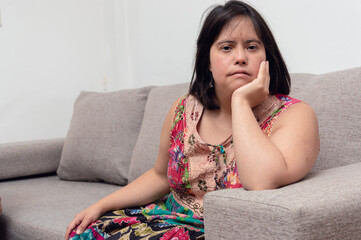 latin caucasian adult woman sitting on the couch leaning on her hand looking at the camera