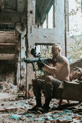 Fototapeta premium a male military soldier in an abandoned building with a gun poses, shoots and takes aim