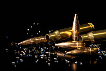 Close-up of disassembled rifle cartridges. Bullet isolated on black background with reflexion. Granulated gunpowder.