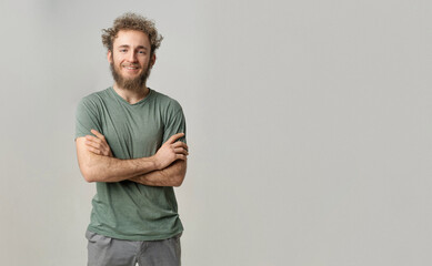 Handsome smiling young handsome bearded wild curly hair man with bright blue eyes isolated on white background. Young thinking man in green tshirt on white background