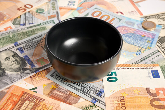 Ceramic bowl - photo on money bank notes. Ceramic black bowl is laying on money bank notes. Dollar and Euro banknotes as background for ceramics. Empty cup on financial background. Expensive cost.