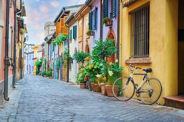 Türaufkleber Schmale Straße des Fischerdorfes San Guiliano mit bunten Häusern und einem Fahrrad am frühen Morgen in Rimini, Italien © Igor