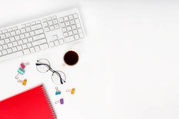 Top view of a modern office desk with a notepad, glasses, keyboard and a coffee or tea cup on a white background with a place for text