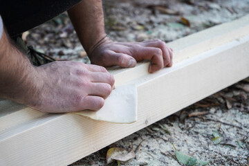  Man hands smoothing wood board using sandpaper. Sanding and polishing wood  plank.                              DIY Crafting at home