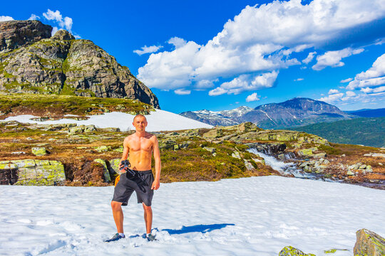 Man in snow in summer at Hydnefossen waterfall Hemsedal Norway.