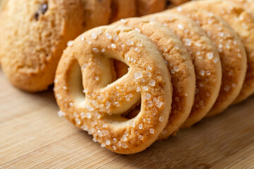 Sugar pretzel macro. Crispy shortbread pretzels with sugar in a row on a wooden background. Tasty butter biscuits. Baked pastry for breakfast. Sweet food, dessert and snack concepts.