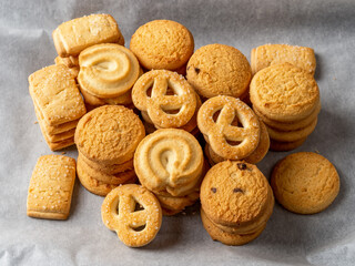 Stacked crispy butter biscuits on a white baking parchment. Variety of shortbread cookies with sugar close-up. Tasty baked pastry. Concepts of sweet food, snack and breakfast baking.