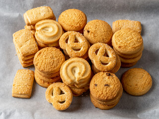 Stacked crispy butter biscuits on a white baking parchment. Variety of shortbread cookies with...