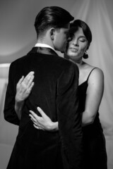 Passion in love woman hugs man standing back to camera. Husband and wife after a romantic dinner. Romance in relationships. Beautiful young couple in home interior. Black and white photo