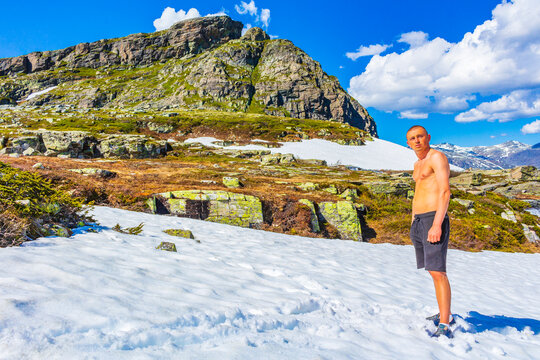 Man in snow in summer at Hydnefossen waterfall Hemsedal Norway.