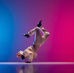 Free fall. Studio shot of young flexible sportive man dancing breakdance in white outfit on...