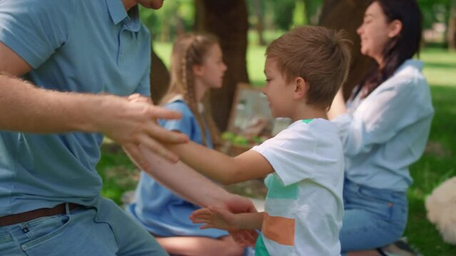 Middle age father tickling son on picnic closeup. Active family play funny games