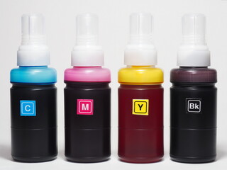 Four plastic bottles with different inks for ink-jet printer on a white background. Repairs and maintenance inkjet printers