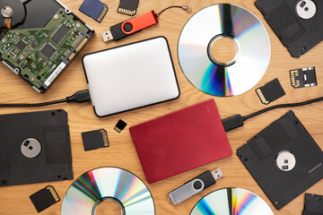 Data storage devices such as CDs, hard drives, pen drives and other, top view on a wooden background