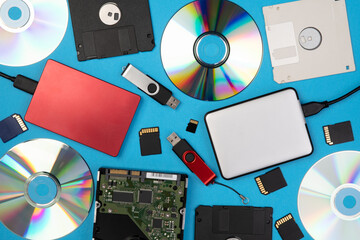Data storage devices such as CDs, hard drives, pen drives and other, top view on a blue background