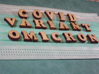 The word covid variant omicron in wooden letters on the face mask. High quality photo