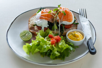 Toast with poached eggs, tomato and salmon on plate in cafe, breakfast time