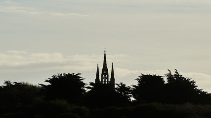 Calvary Church in France. Religious building with 3 spires silhouetted against light. Front view.