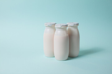 Bottles with probiotics and prebiotics dairy drink on light blue background. Bio yogurt with useful microorganisms. Production with biologically active additives. Fermentation and diet healthy food.