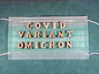 The word covid variant omicron in wooden letters on the face mask. High quality photo